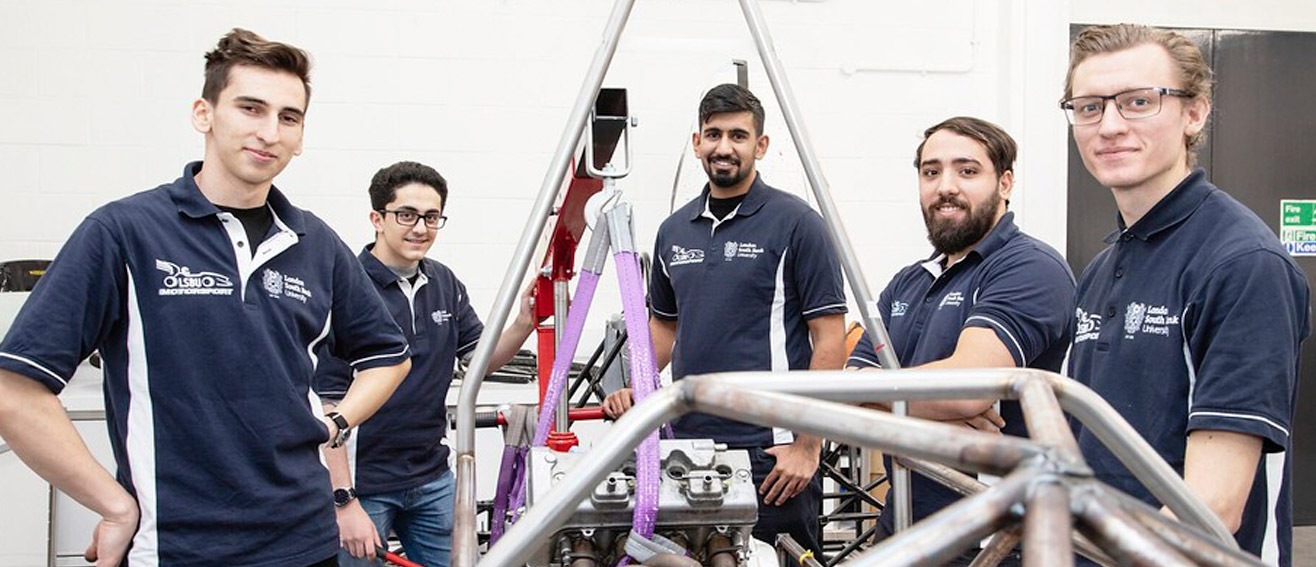 happy men next to fixed car engine