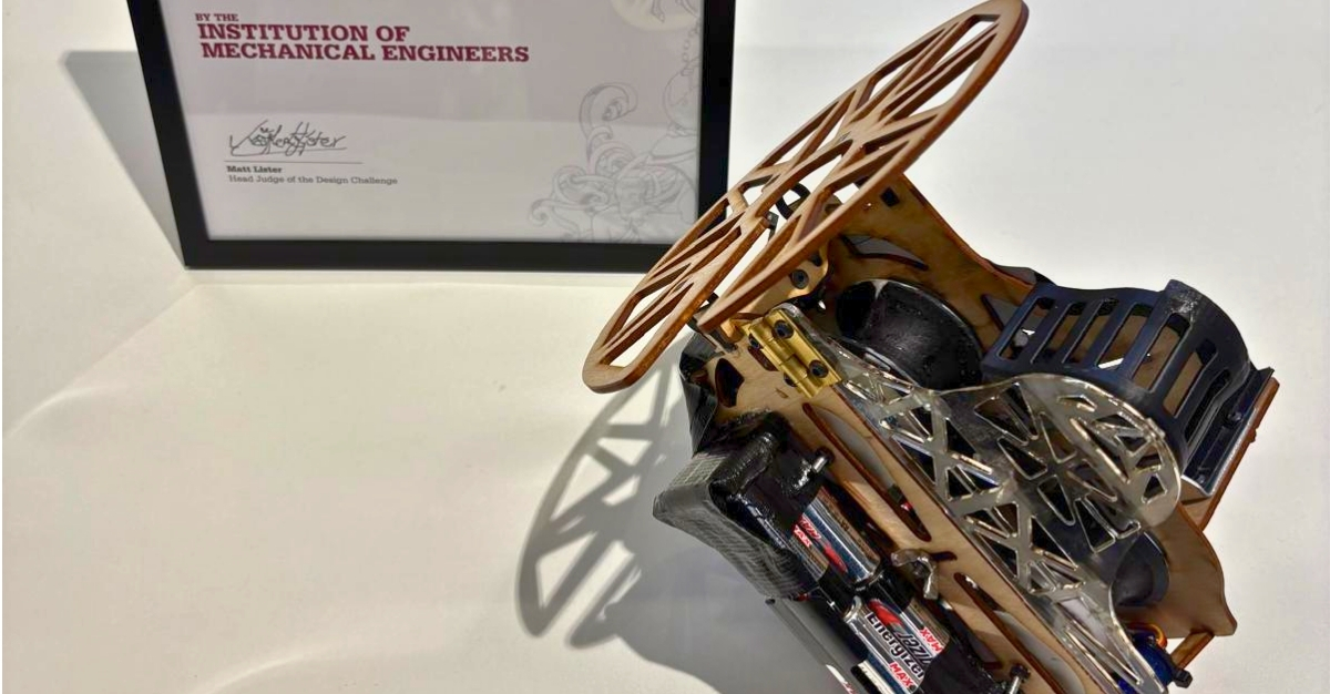 A mechanical device with cogs sits on a table next to a certificate in a black frame