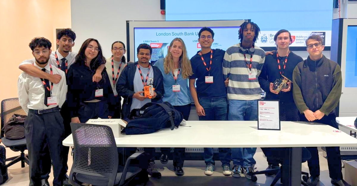 A large group of young men and women stand in front a screen looking at the camera