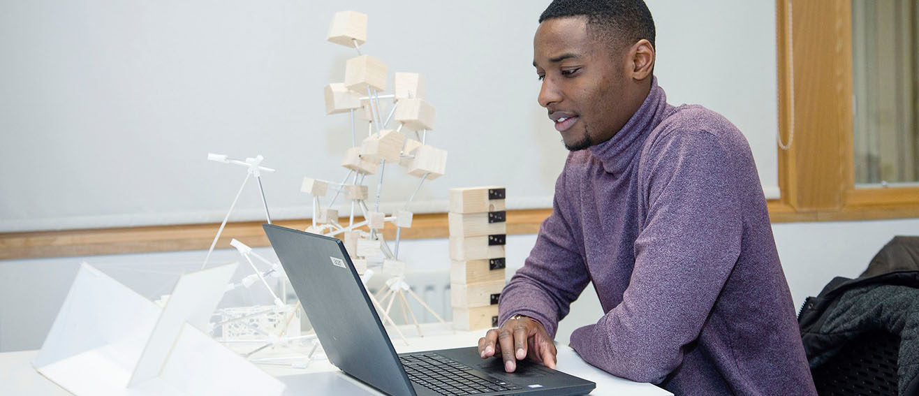 Man in purple jumper on laptop 1316x567