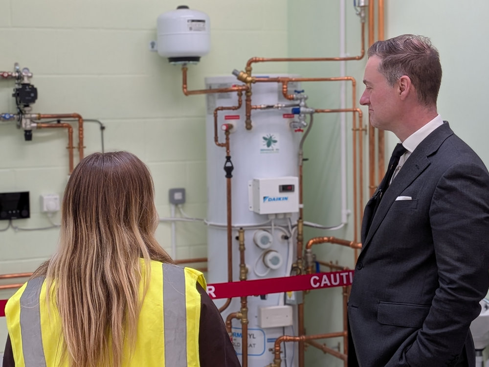 A man and a woman stand together looking at a boiler