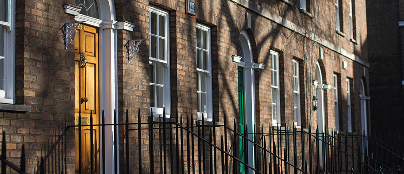 terraced houses with black railings and different coloured doors