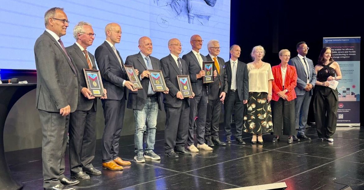 A group of men stand on a stage holding awards