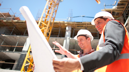 Construction workers study plans on-site