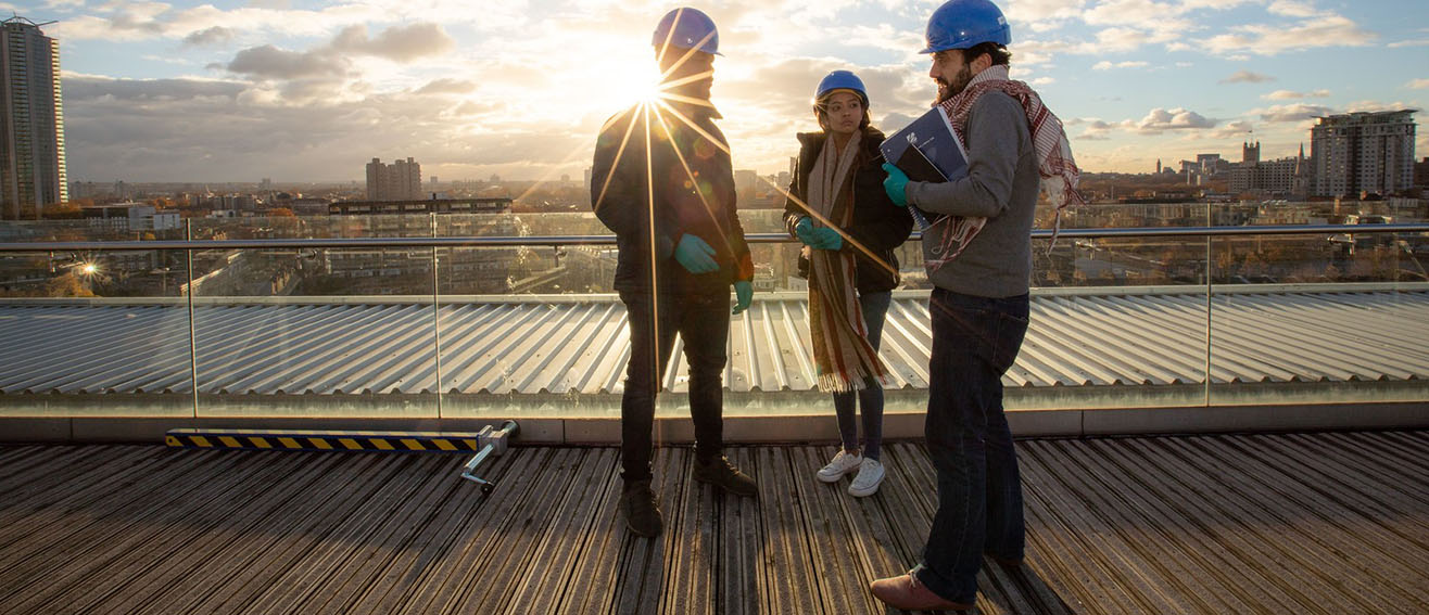 Students in construction hats talk 1316x567