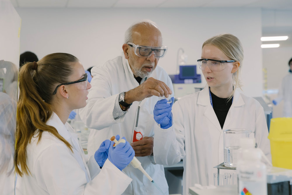 A teacher works with two students in a lab setting