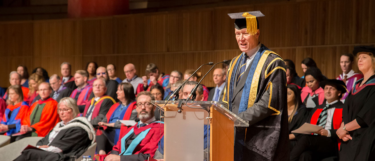 man at lectern at graduation