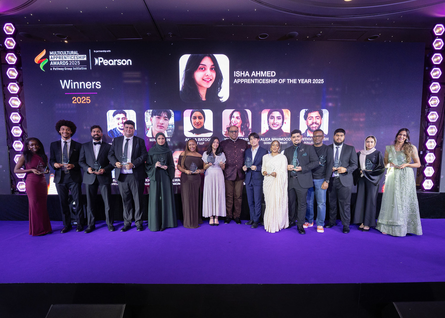A group of people holding awards and standing in front of a large screen
